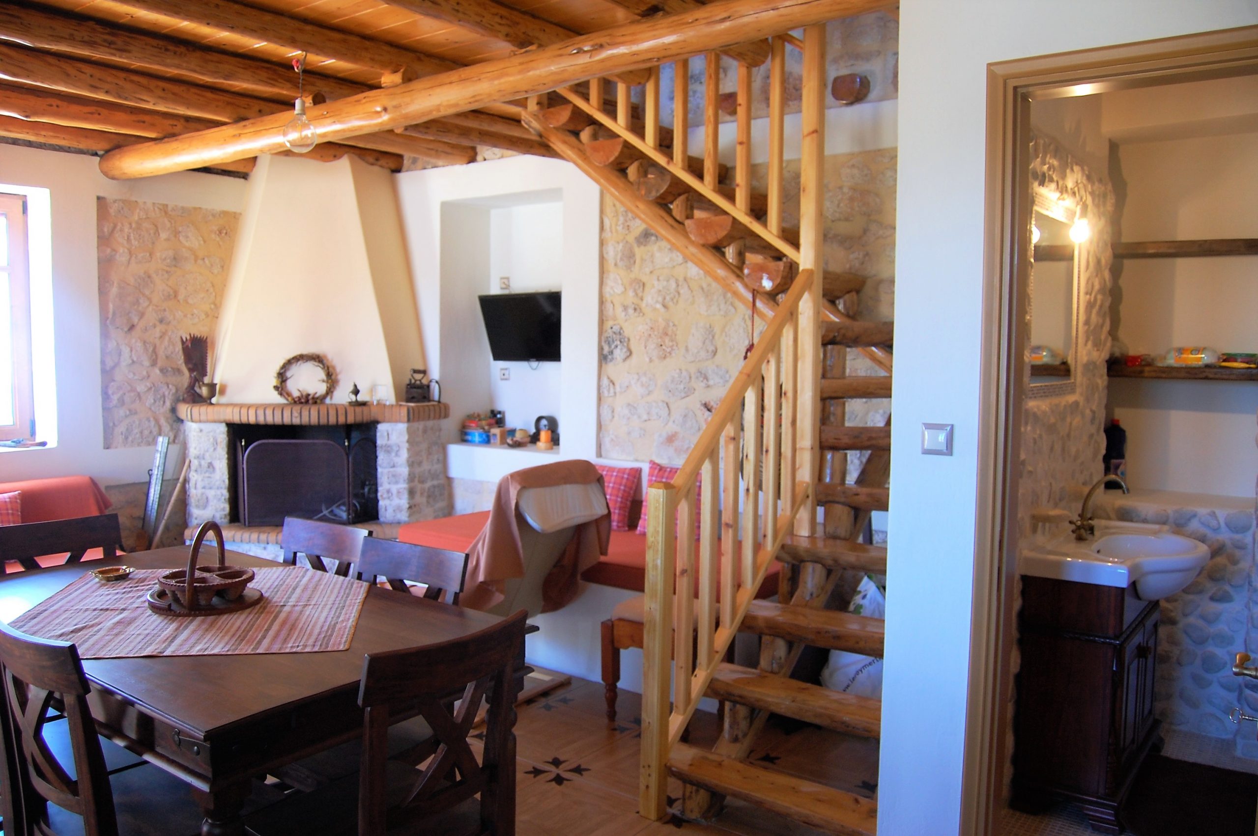 Open plan lounge with wooden staircase of stone house for rent Ithaca Greece